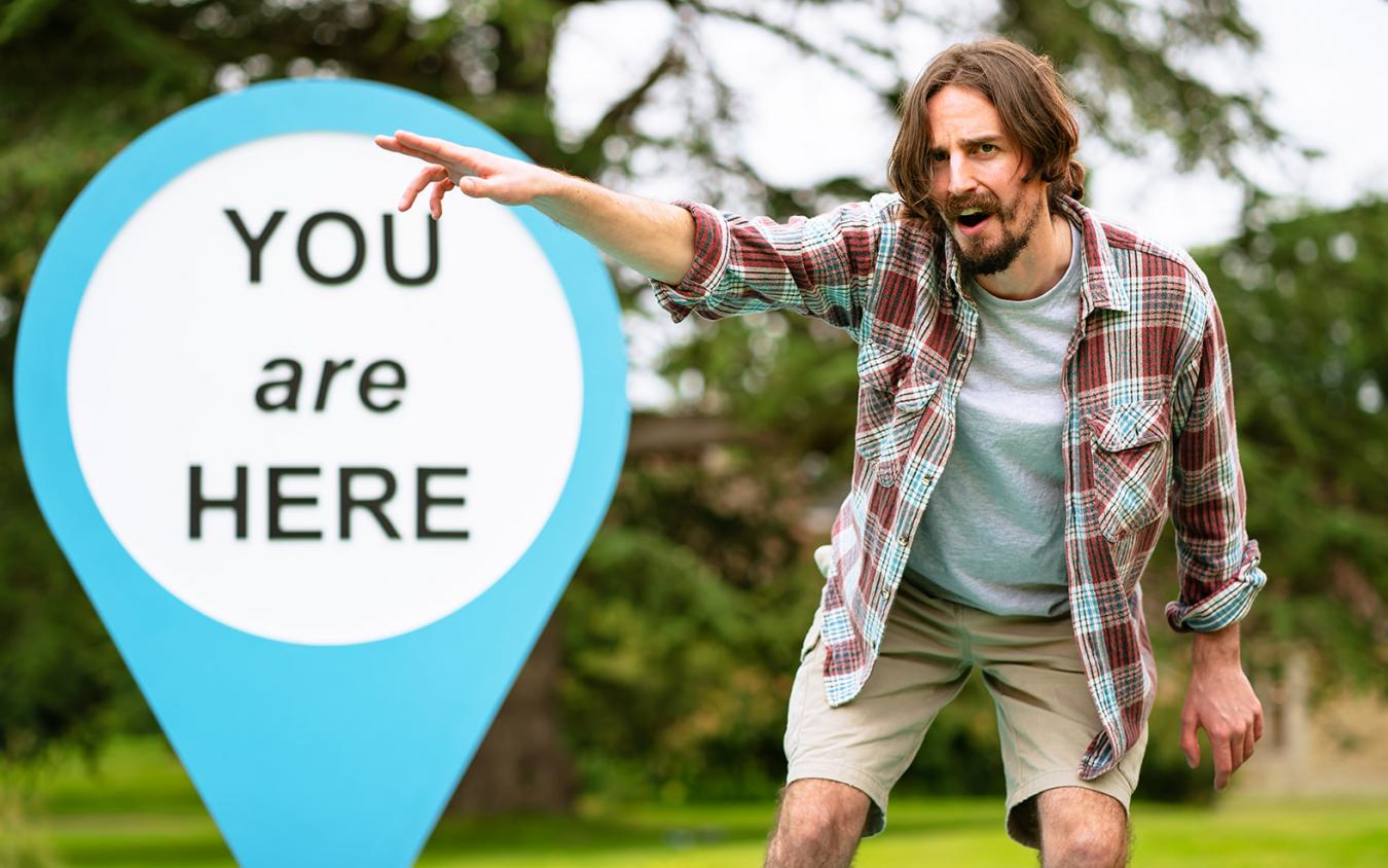 Photo of Harry Egan pointing with You Are Here Sign in background